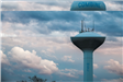 A white City of Combine water tower against a blue, cloudy sky.