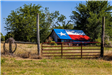 An image of a rustic old barn with the roof painted as a bright Texas flag.