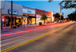 An image of timelapse car tail lights whisking by the shops in old downtown Forney.