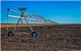 An image of a very large irrigation system on some newly plowed crop. 