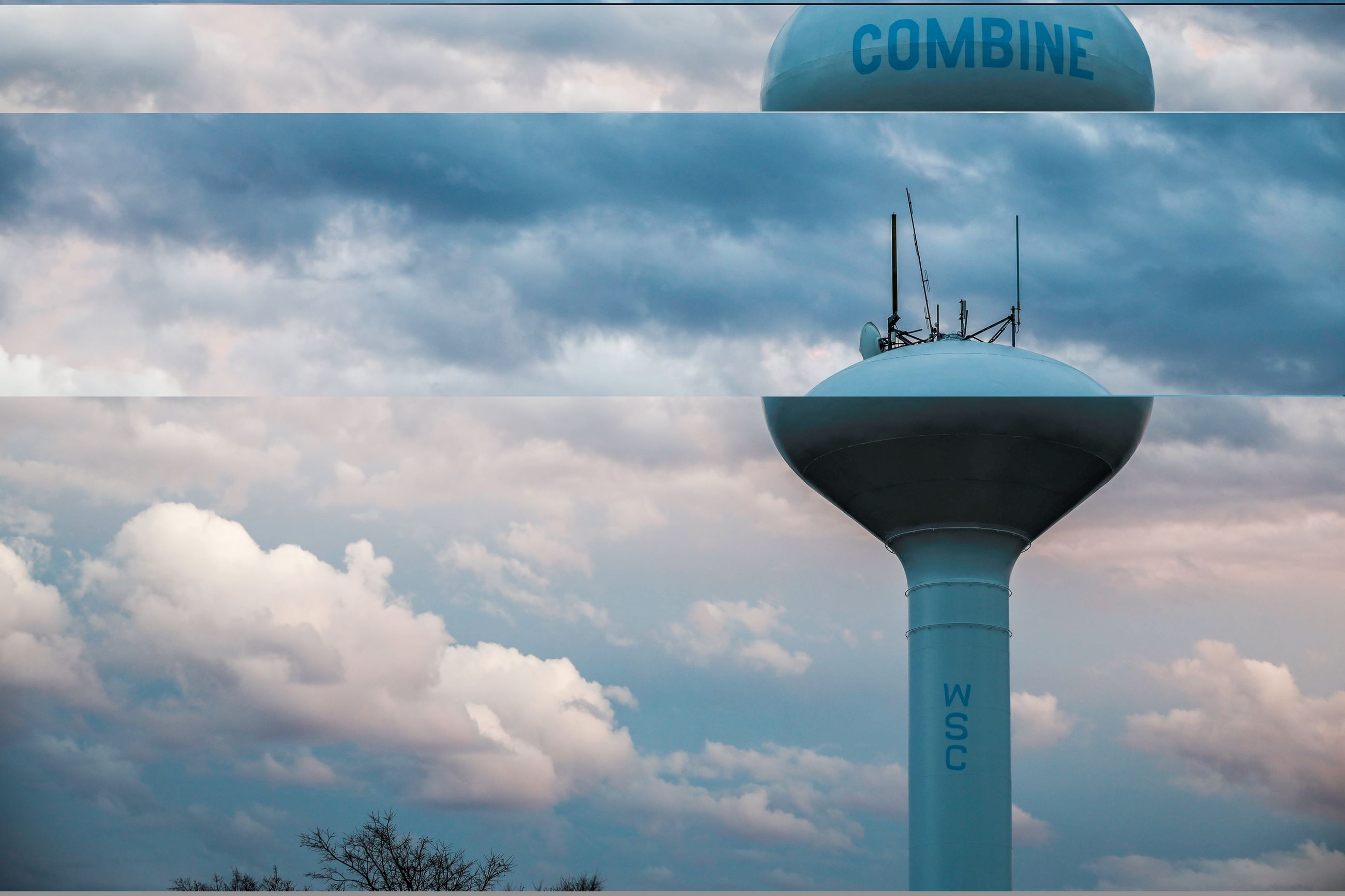 A white City of Combine water tower against a blue, cloudy sky.