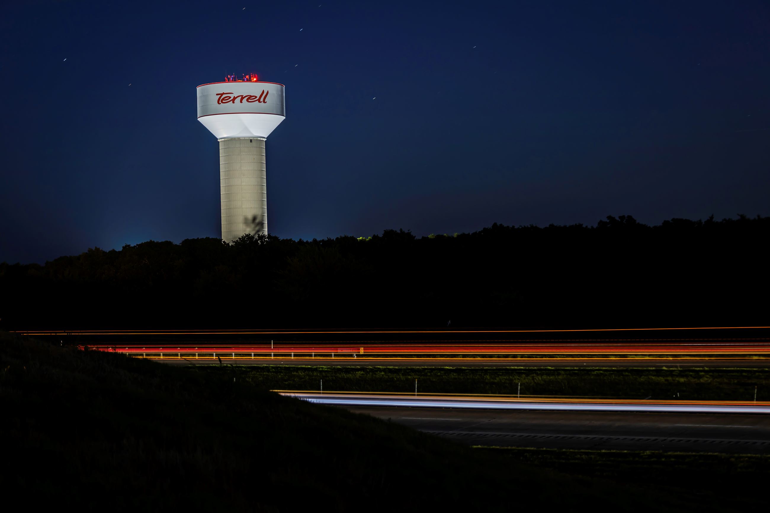An image of teh Terrell water tower all lit up at night on US 80.