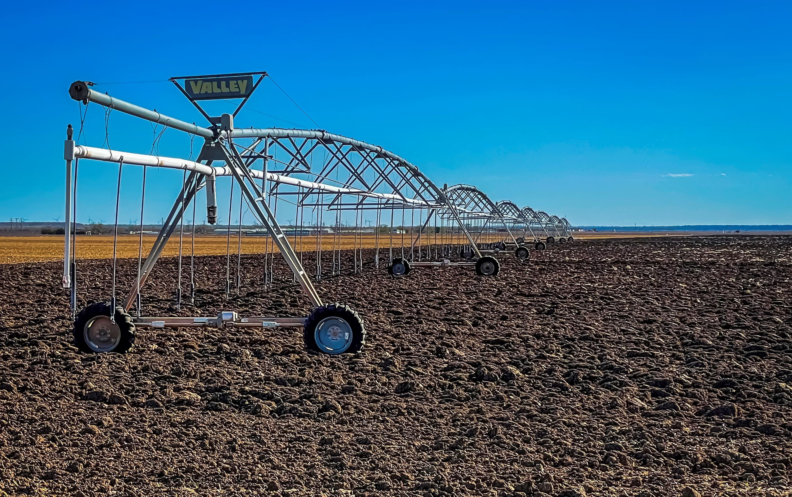 An image of a very large irrigation system on some newly plowed crop. 